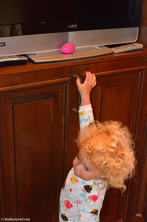 Katie isn't quite tall enough to reach the egg under the TV
