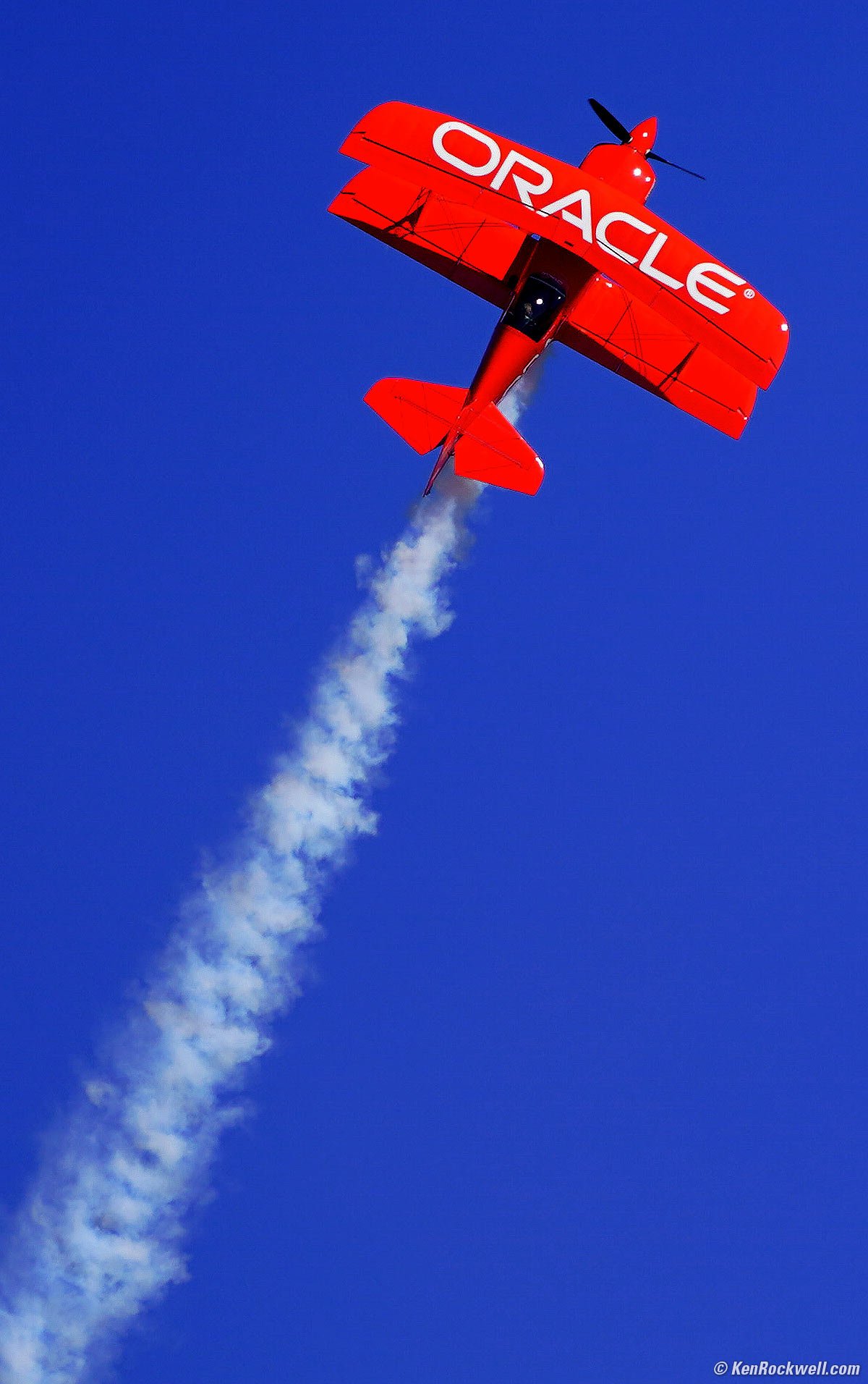 Red Biplane against Blue Sky with Smoke Trail